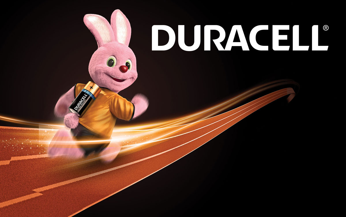 A pink mascot rabbit in a yellow shirt holding a Duracell battery runs energetically on a track.