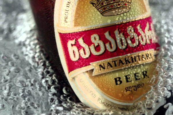 A wet bottle of Natakhtari beer with a crown emblem and Georgian script on the label.
