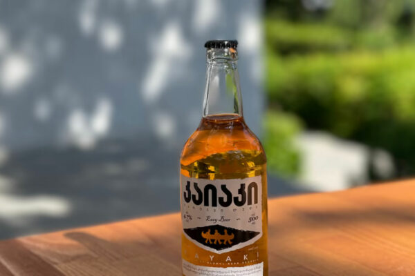 A bottle of Georgian Ayakhi easy beer, 5 percent alcohol, placed on a wooden surface.