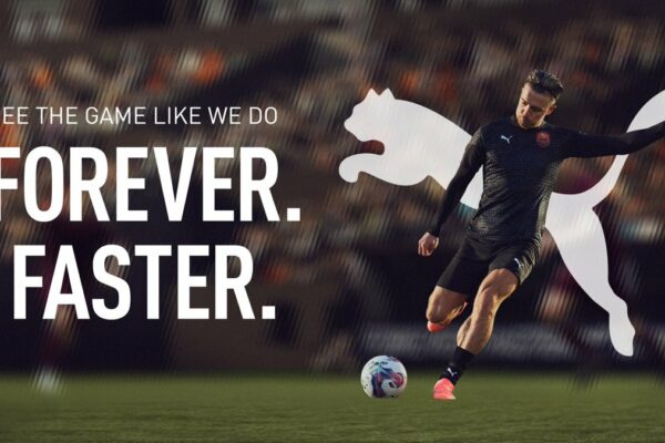 A soccer player in motion kicks a ball on a field, with Puma branding and text promoting forever-fast performance.